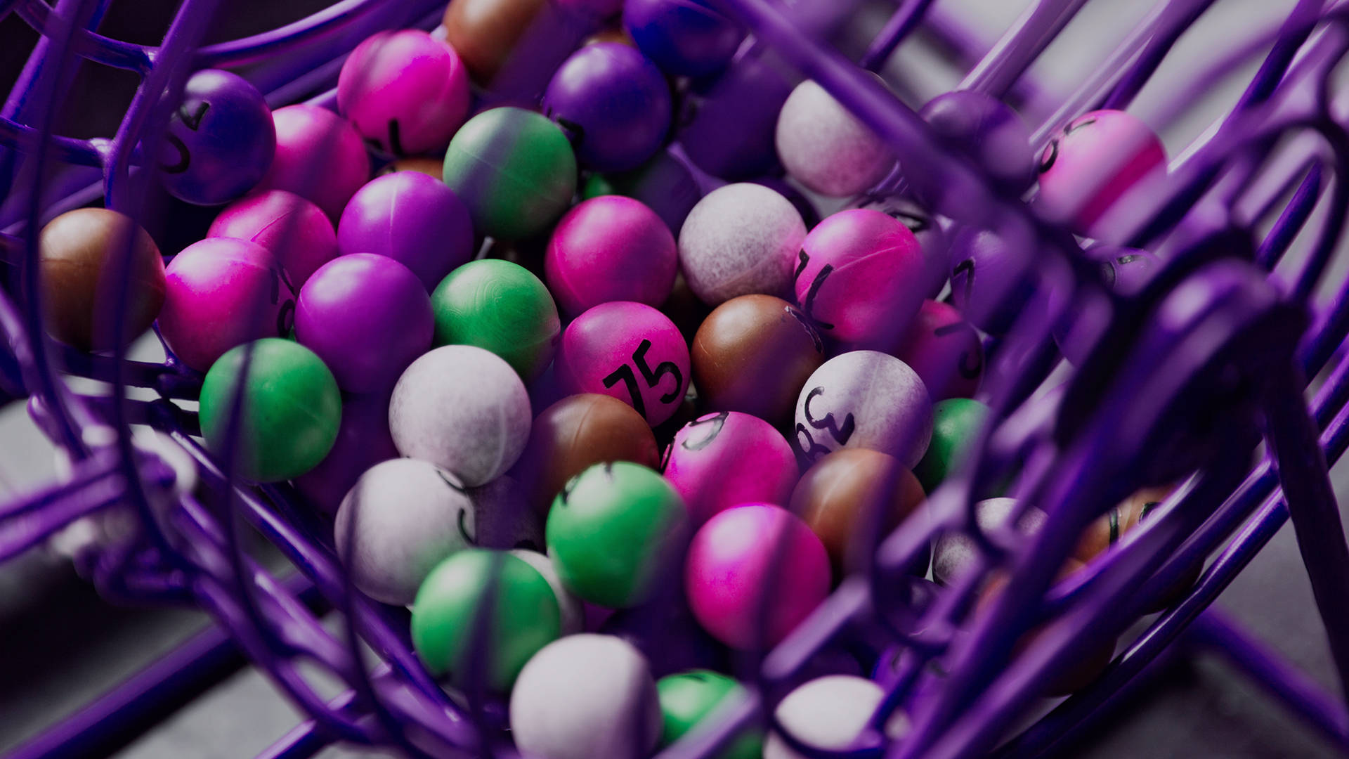 A bingo ball cage filled with multicoloured balls